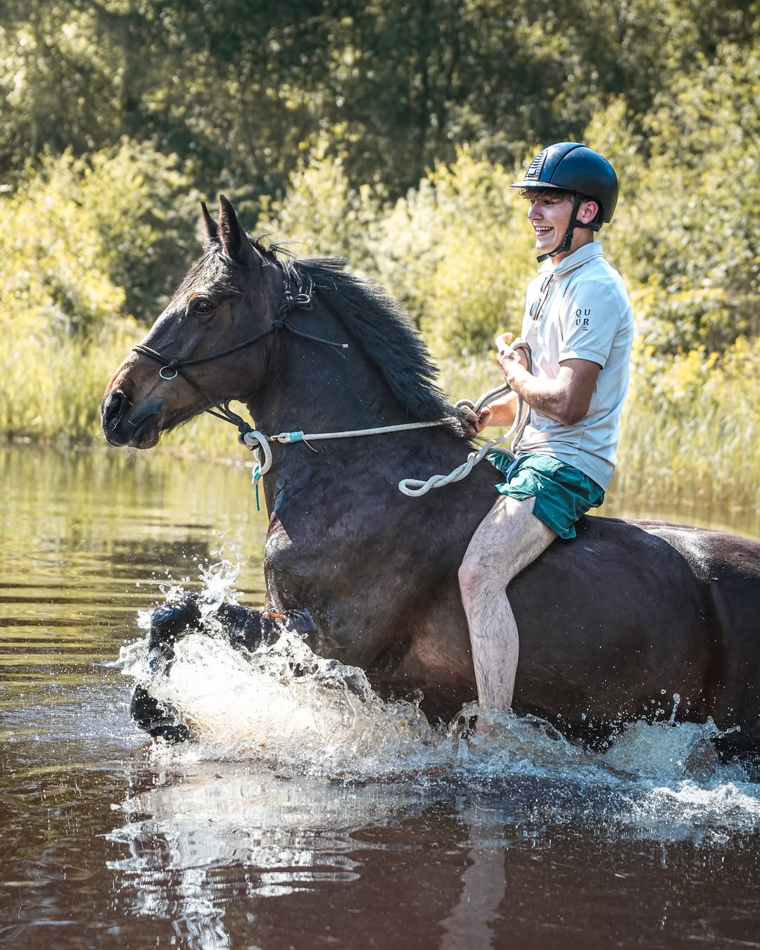 Robin rijdt lachend met alleen een touwhalster door het water